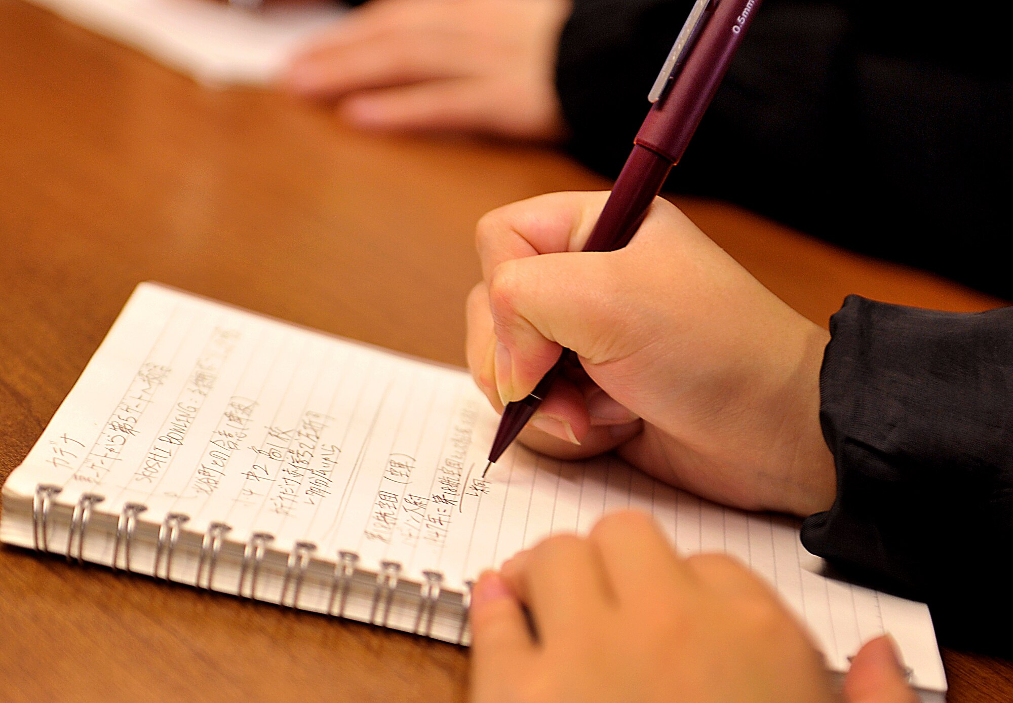 A student from the Okinawa International University takes notes during a typhoon brief by U. S. Air Force Capt. Elizabeth Hudson, 909th Air Refueling Squadron chief of wing plans and KC-135 Stratotanker pilot, on Kadena Air Base, Japan, Feb. 23, 2015. The students visited Kadena Air Base to learn about disaster prevention procedures and observe the Kadena tsunami evacuation route first-hand. (U.S. Air Force photo by Naoto Anazawa)