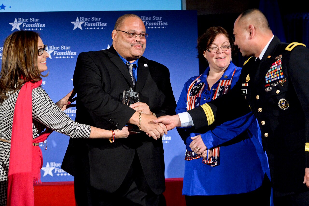 Army Brig. Gen. James Wong, right, congratulates Mark Johnson, second from left, the recipient of the Blue Star Neighbor award, at the Blue Star Families Fifth Anniversary Celebration in Washington, Feb. 24, 2014. Wong is the assistant to the National Guard's acting director. Kathy Roth-Douquet, left, founder and CEO of Blue Star Families, and Kelly Durkee-Erwin, third from left, who nominated Johnson, participated in the event. DoD photo by EJ Hersom