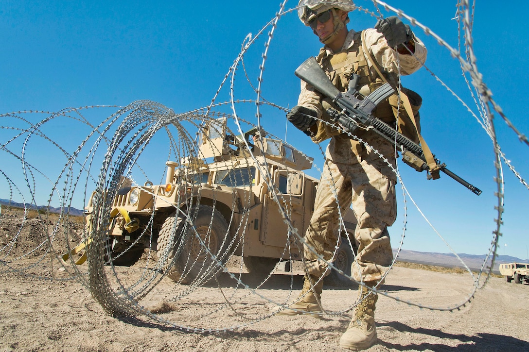 Marine Corps Lance Cpl. Christian Garcia uncoils concertina wire while participating in Integrated Training Exercise 2-15 at the Marine Corps Air Ground Combat Center in Twentynine Palms, Calif., Feb. 15, 2015. Garcia is a water support technician assigned to Combat Logistics Battalion 13, 1st Marine Logistics Group.