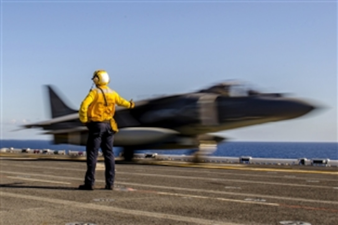 Navy Petty Officer 3rd Class Alex Williams signals to an AV-8B Harrier as it takes off from the flight deck of the amphibious assault ship USS America in the Pacific Ocean, Feb. 23, 2015. The America is conducting maritime training off the coast of California. 

