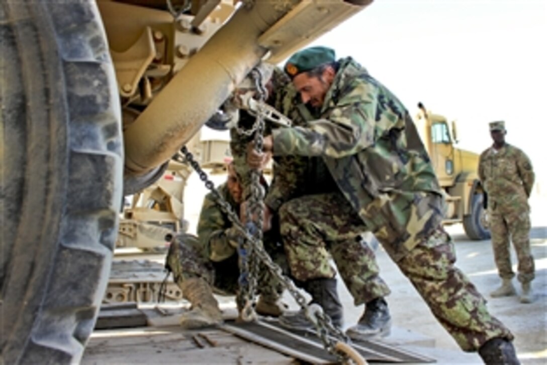 A U.S. soldier observes as Afghan soldiers load vehicles onto a truck for transfer to Afghan security forces on Bagram Airfield, Afghanistan, Feb.14, 2015.