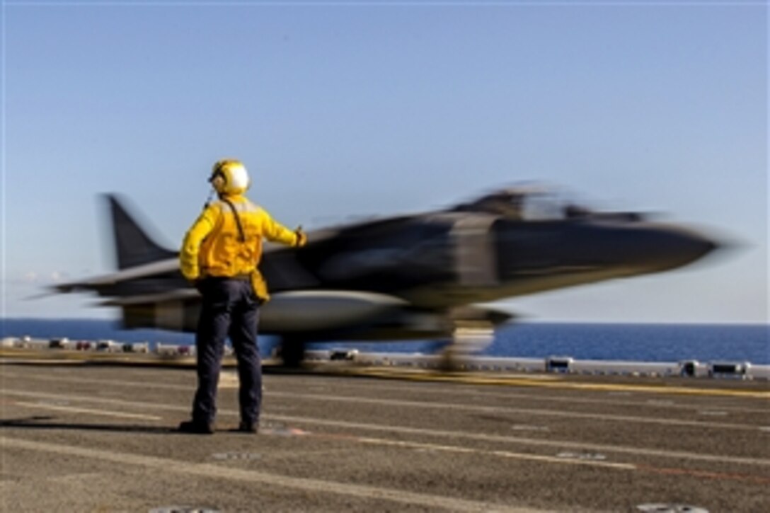 Navy Petty Officer 3rd Class Alex Williams signals to an AV-8B Harrier as it takes off from the flight deck of the amphibious assault ship USS America in the Pacific Ocean, Feb. 23, 2015. The America is conducting maritime training off the coast of California. 

