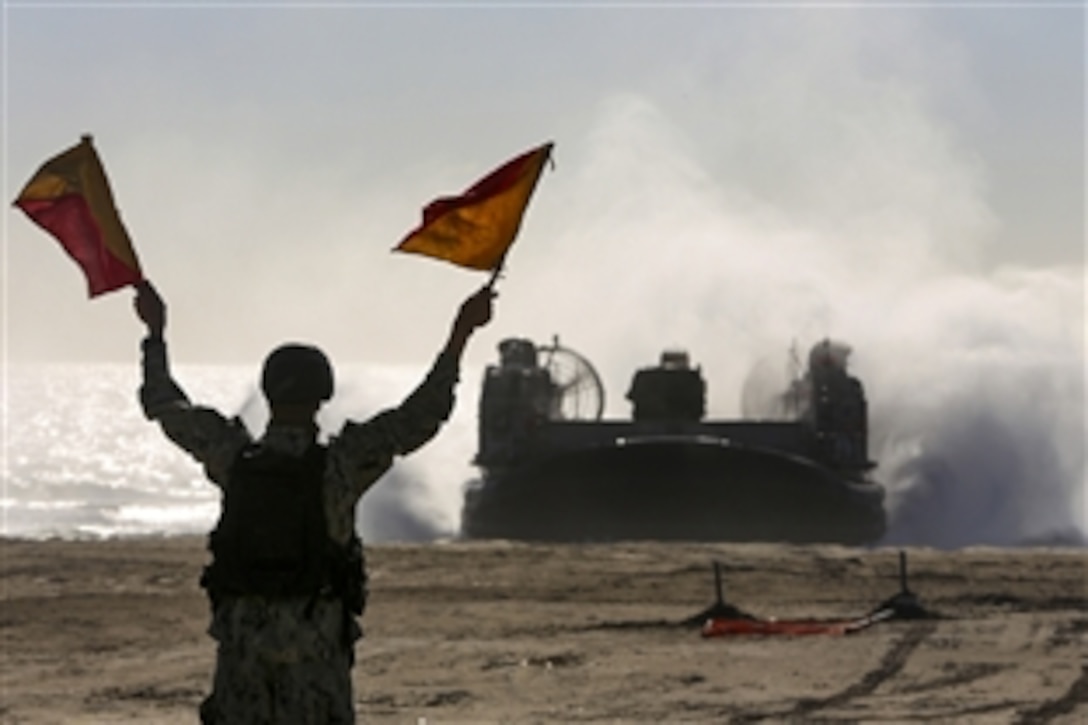 A Navy sailor directs a landing craft air cushion onto the beach during an offload from the amphibious transport dock ship USS San Diego on Camp Pendleton, Calif., Feb. 23, 2015. 