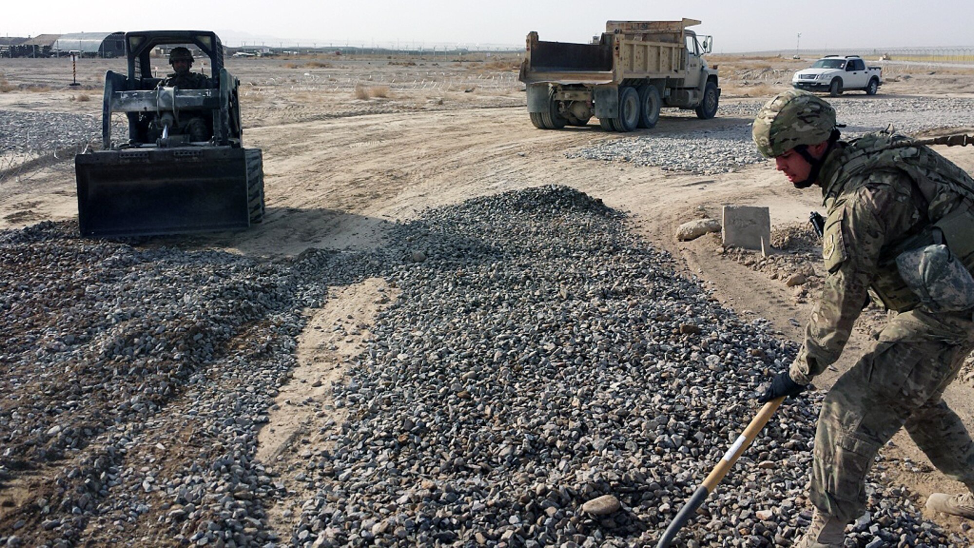 U.S. Air Force 1st Lt. Tim Lord, 451st Expeditionary Support Squadron Civil Engineer flight commander, lays gravel across an access road Feb. 13, 2015 at Kandahar Airfield, Afghanistan. Part of a two-man team, Lord and his enlisted counterpart, Staff Sgt. Gabriel Lara-Ortega, 451 CE Flight NCOIC in charge, execute the functions of an average Air Force civil engineer squadron, usually comprised of more than 100 Airmen. (U.S. Air Force courtesy photo/released)