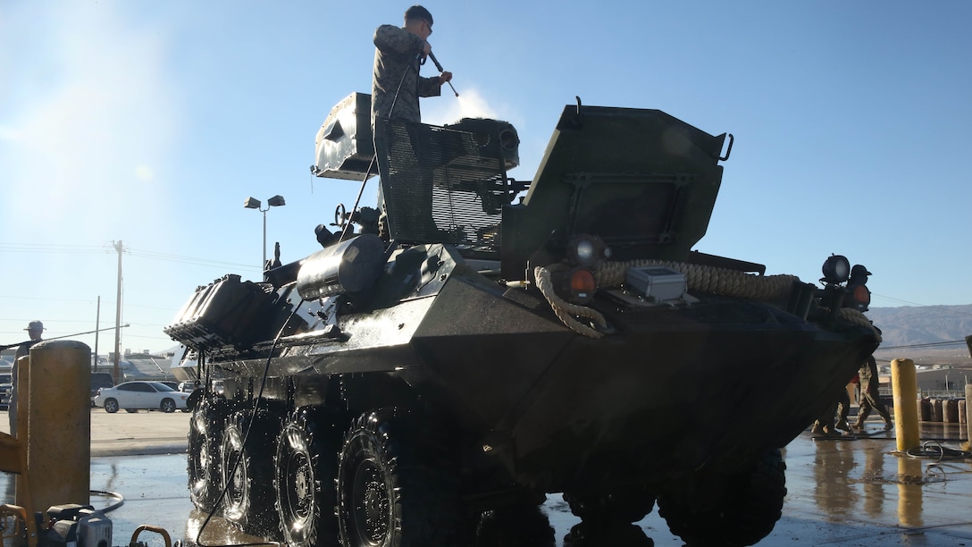 A 3rd Light Armored Reconnaissance Battalion Marine cleans off excess dirt from a Light-Armored Vehicle equipped with a new Anti-Tank weapons system at the 3rd LAR ramp prior to operational testing on range 500 aboard the Combat Center, Feb. 10, 2015. 3rd LAR has been training alongside 1st Tank Battalion and 1st LAR during operational testing of the new system.