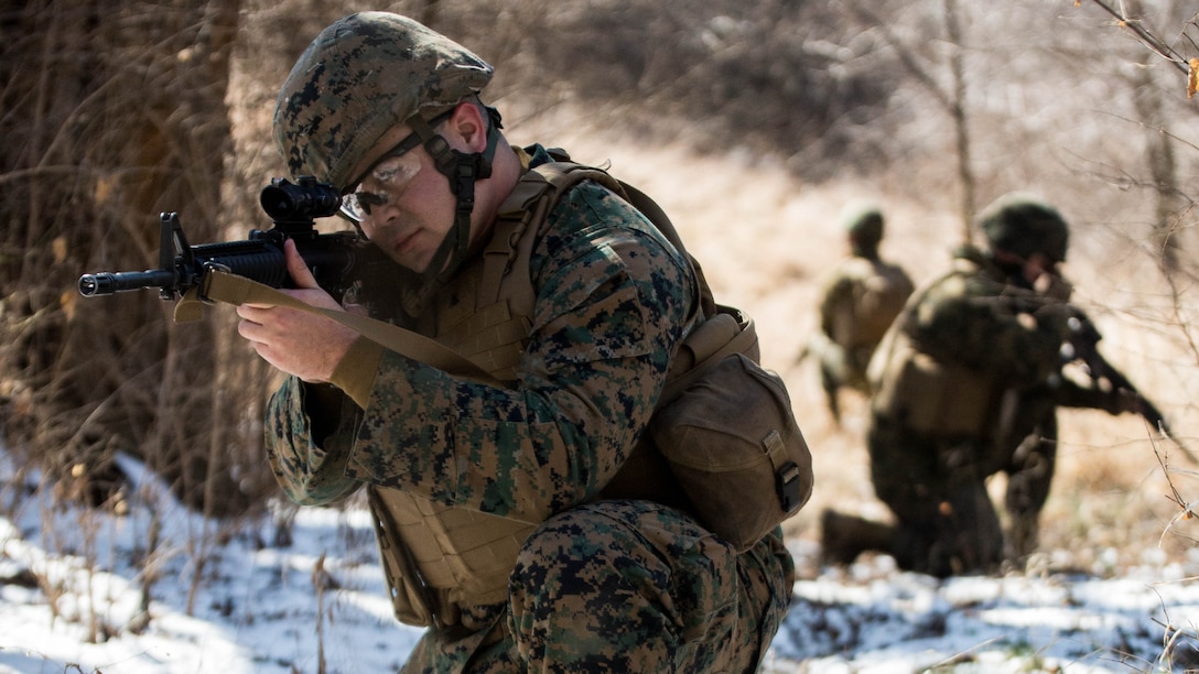 Cpl. Joseph Howell, a tactical switching operator with Combat Logistics Regiment 4, 4th Marine Logistics Group, kneels down and takes account of his surroundings on a patrol during the Marine Expeditionary Force Exercise in Kansas City, Mo., Feb. 22, 2015. Howell was part of the acting guard force during the exercise with I MEF. The exercise enabled Marines to improve interoperability between the active and Reserve component, while preparing them with a realistic training environment at the force level.