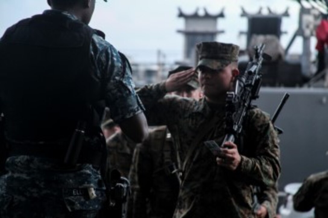 A U.S. Marine salutes the sentry while embarking onto the USS Essex (LHD 2) prior to Amphibious Squadron/Marine Expeditionary Unit Integration Training (PMINT) aboard Naval Base San Diego Feb. 22, 2015. The 15th MEU is embarked aboard the three ships of the Essex Amphibious Ready Group - the USS Essex, USS Anchorage (LPD 23), and USS Rushmore (LSD 47) – during PMINT to continue integrating and training with the PHIBRON and ship staffs as they prepare for deployment later this spring. (U.S. Marine Corps photo by Cpl. Elize McKelvey/Released)