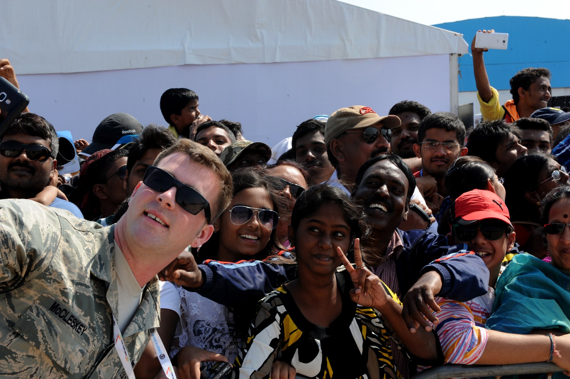 U.S. Air Force Senior Airman Robert McCleskey, 44th Aircraft Maintnance Unit F-15 crewchief, takes selfies with visitors phones from the Aero India crowd during Aero India at Air Force Station Yelahanka, Bengaluru, India, Feb. 22, 2015. Aero India is India's premier aerospace exhibition and airshow and allows the United States to demonstrate its commitment to the security of the Indo-Asia-Pacific region and showcase defense aircraft and equipment, which ultimately contributes toward better regional cooperation and tactical compatibility with other countries.  This year marks the 10th iteration of Aero India since its inception in 1996.  (U.S. Air Force photo by Airman 1st Class Stephen G.Eigel/Released)