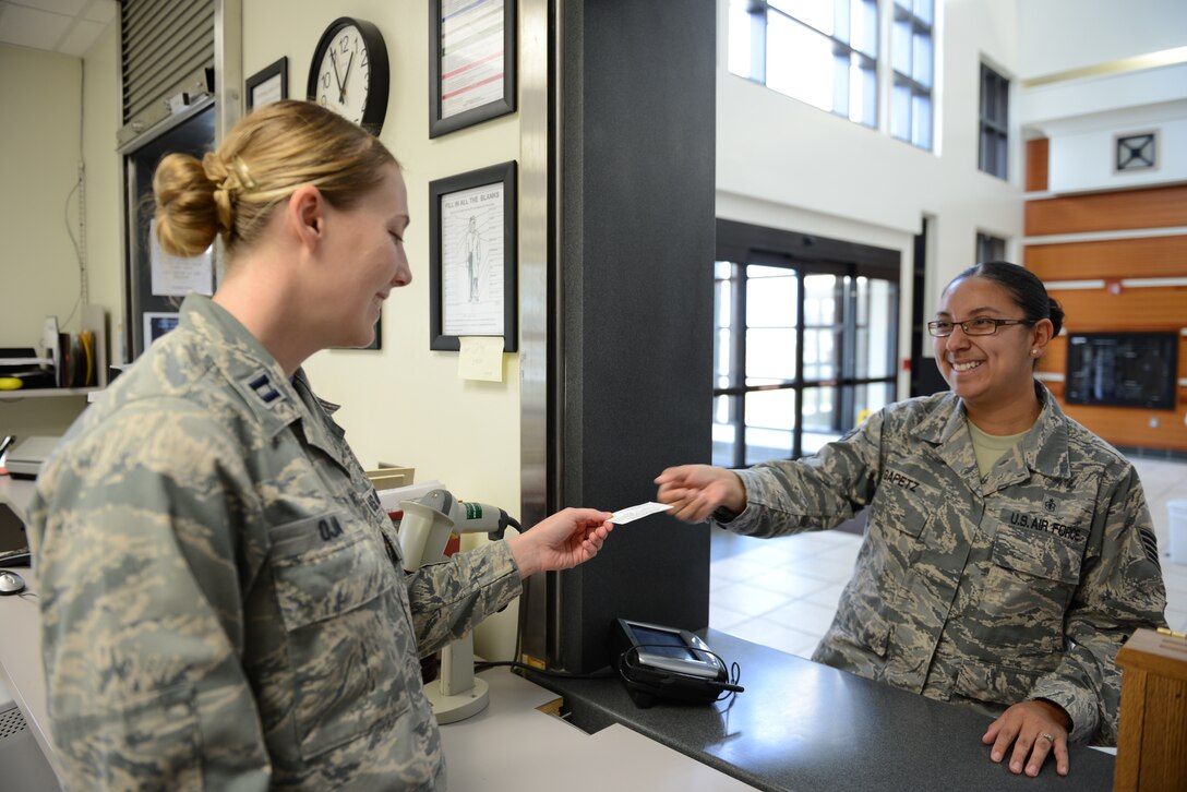 Capt. Kathryn Oja, 36th Medical Group pharmacist, receives a Self-Initiated Care Kit card from Staff Sgt. Sarai Gapetz, a patient at 36th MDG, Feb. 20, 2015, at Andersen Air Force Base, Guam. The pharmacy has processed more than 80 prescriptions since the beginning of this month for S.I.C.K. patients. (U.S Air Force photo by Airman 1st Class Arielle Vasquez/Released)
