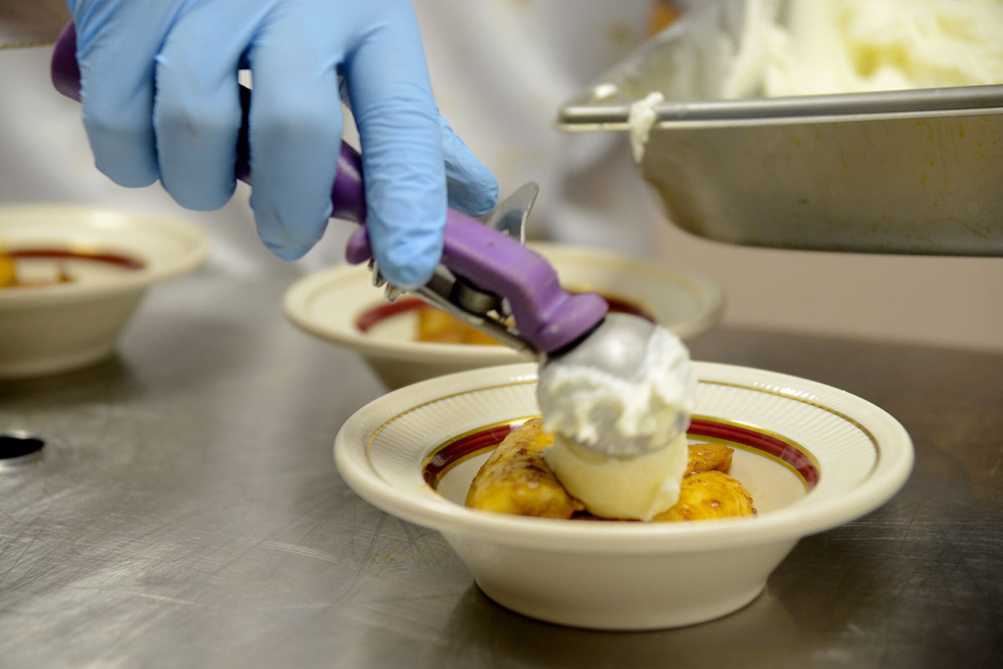 The dessert had to be served quickly because the vanilla ice cream would melt on the banana flambé so ‘Team Alaska’ had to work as a team to add the caramel sauce and cherry spun sugar garnish fast enough for it to all hold together and be served at the Kenai Dining Hall on Feb. 20, 2015. The 10-person team of Soldiers and Airmen tried to make a five-star three-course meal from an Army field kitchen for JBER leadership to prepare for 40th Annual Military Culinary Arts Competitive Training Event at Fort Lee, VA. March 4-13. (Air Force photo/Airman Christopher R. Morales)