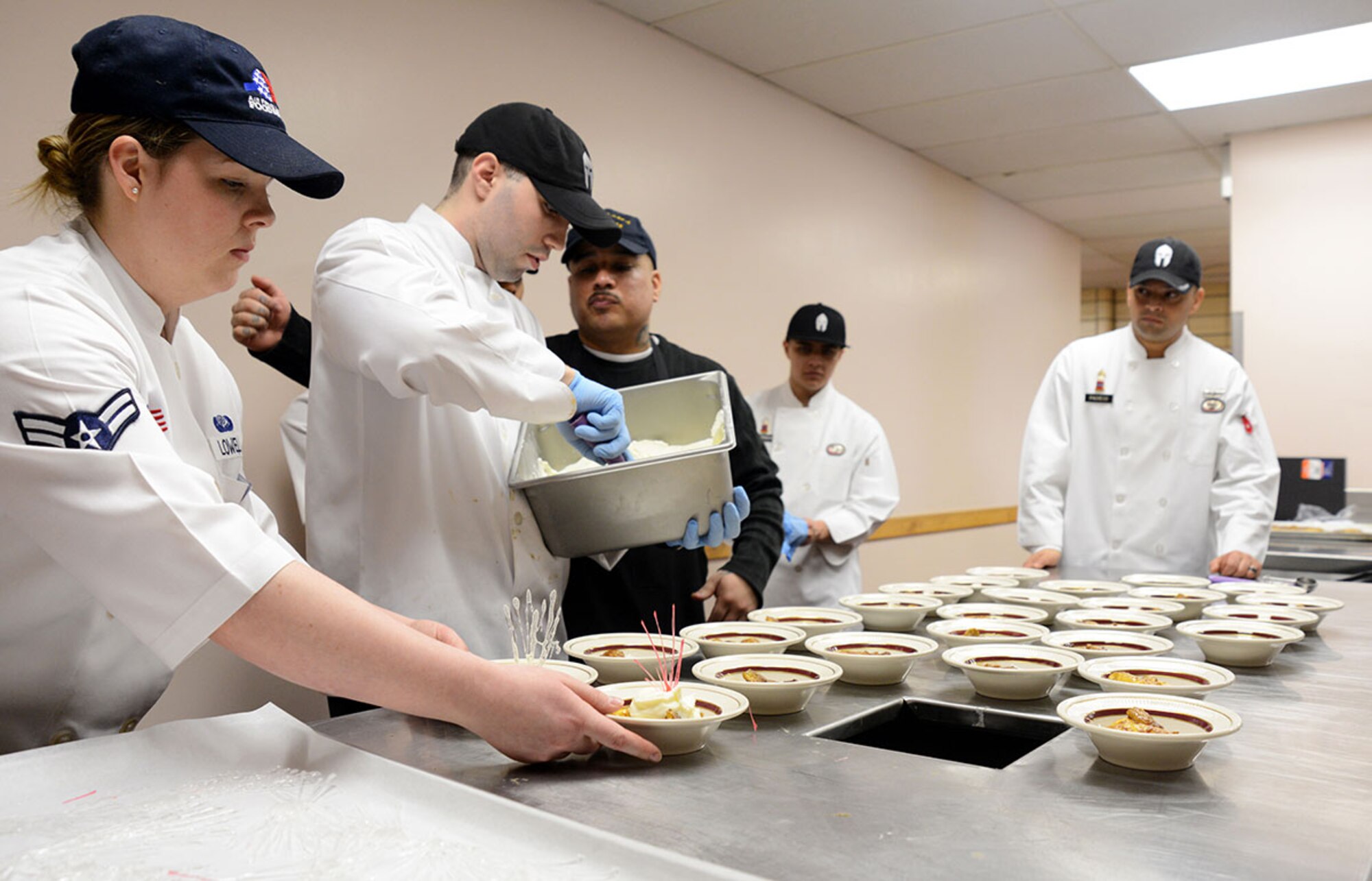 The dessert had to be served quickly because the vanilla ice cream would melt on the banana flambé so ‘Team Alaska’ had to work as a team to add the caramel sauce and cherry spun sugar garnish fast enough for it to all hold together and be served at the Kenai Dining Hall, JBER on Feb. 20, 2015. The 10-person team of Soldiers and Airmen tried to make a five-star three-course meal from an Army field kitchen for JBER leadership to prepare for 40th Annual Military Culinary Arts Competitive Training Event at Fort Lee, VA. March 4-13. (Air Force photo/Airman Christopher R. Morales)