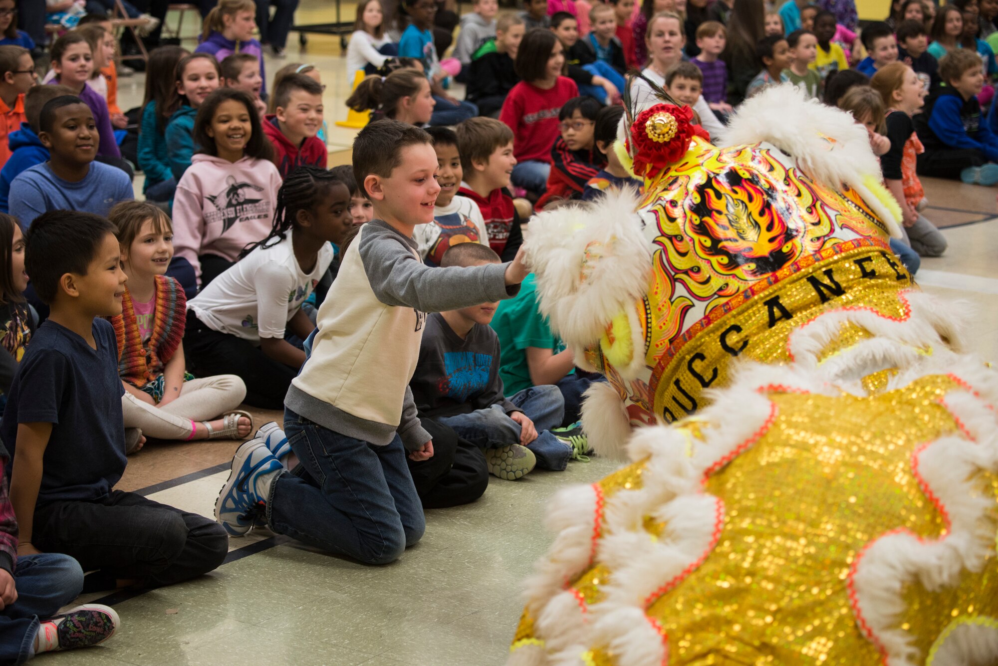 A student of Stephenson Elementary reaches out to pet a traditional lion mascot during an assembly at Mountain Home Air Force Base, Idaho Feb. 23, 2015. The lions surprised the students and preformed to the sound of drums at the end of the presentation. (U.S. Air Force photo by Airman Connor J. Marth/RELEASED)