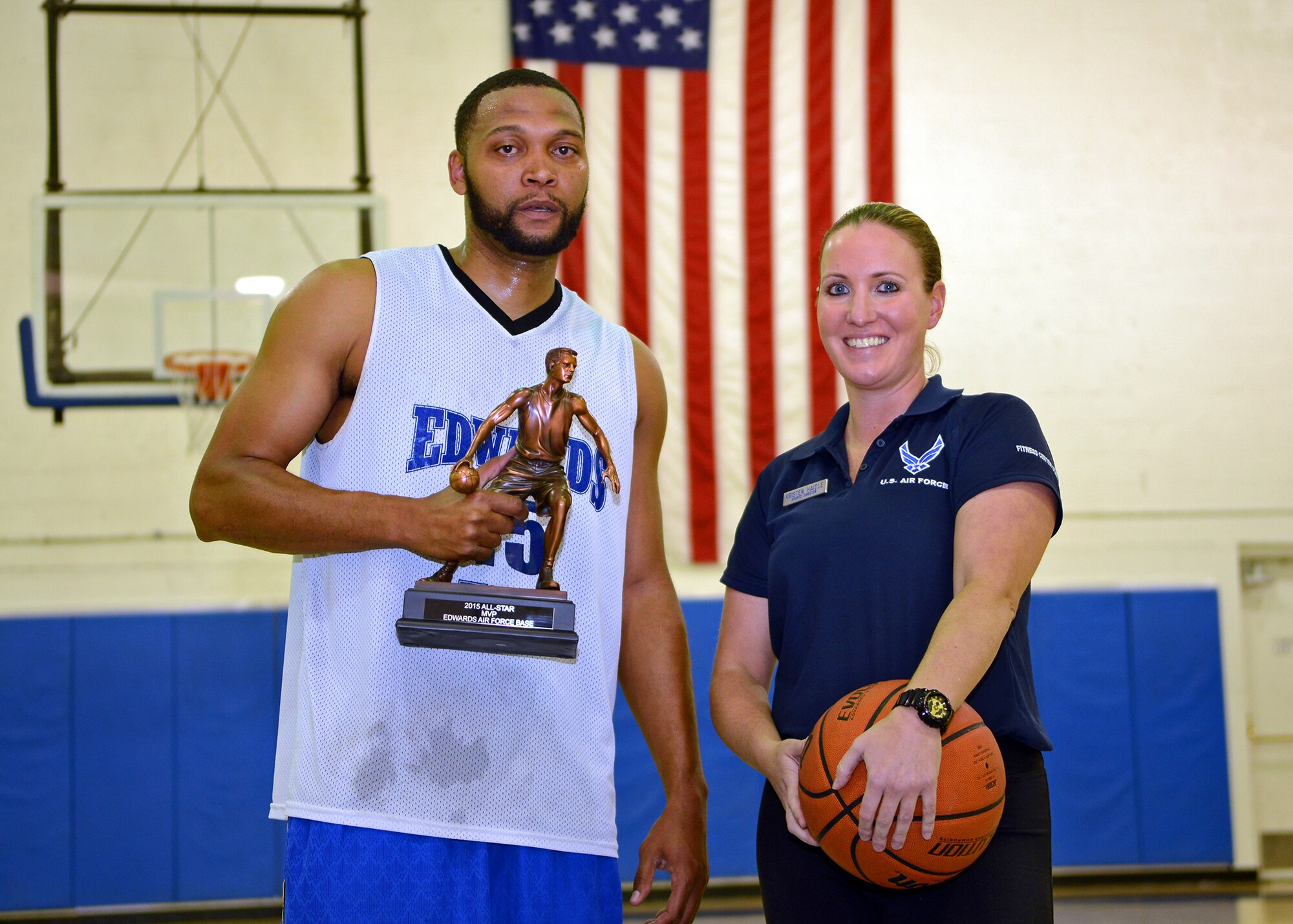 Kristen Haidle (center), 412th Force Support Squadron sports director, presents Sidney Melvin (left), 412th Force Support Squadron, with the MVP trophy after his team won the base's All Star basketball game held Feb. 18. (U.S. Air Force photo by Jet Fabara)