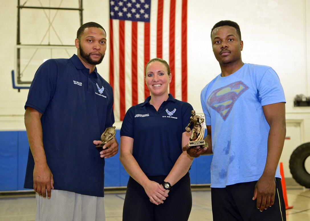 Kristen Haidle (center), 412th Force Support Squadron sports director, presents Sidney Melvin (left), 412th Force Support Squadron, with the three-point shootout trophy and Senior Airman Quadri Carter (right), 412th Security Forces Squadron, with the skills challenge trophy during the base's All Star Basketball Showcase held Feb. 17. (U.S. Air Force photo by Jet Fabara)