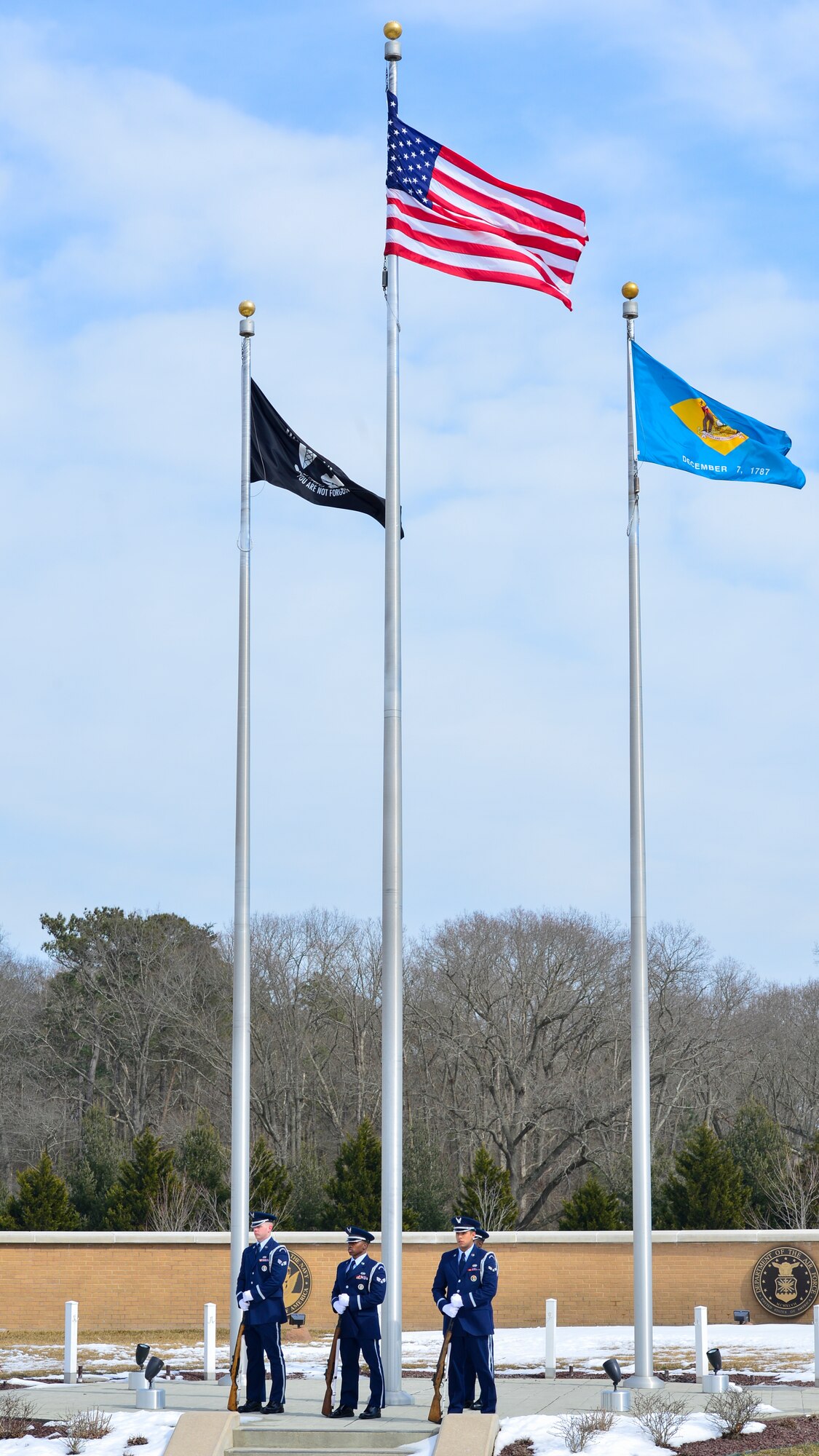 Dover Air Force Base Honor Guard members, Senior Airman James Korte, Senior Airman Tavin Alford and Airman 1st Class Jesus Cervantes-Martinez, stand ready during a funeral Feb. 25, 2015, at the Delaware Veterans Memorial Cemetery in Millsboro, Del. This is one of two Delaware Veterans Memorial Cemeteries, the other being located in Bear, Del. (U.S. Air Force photo/Airman 1st Class Zachary Cacicia)