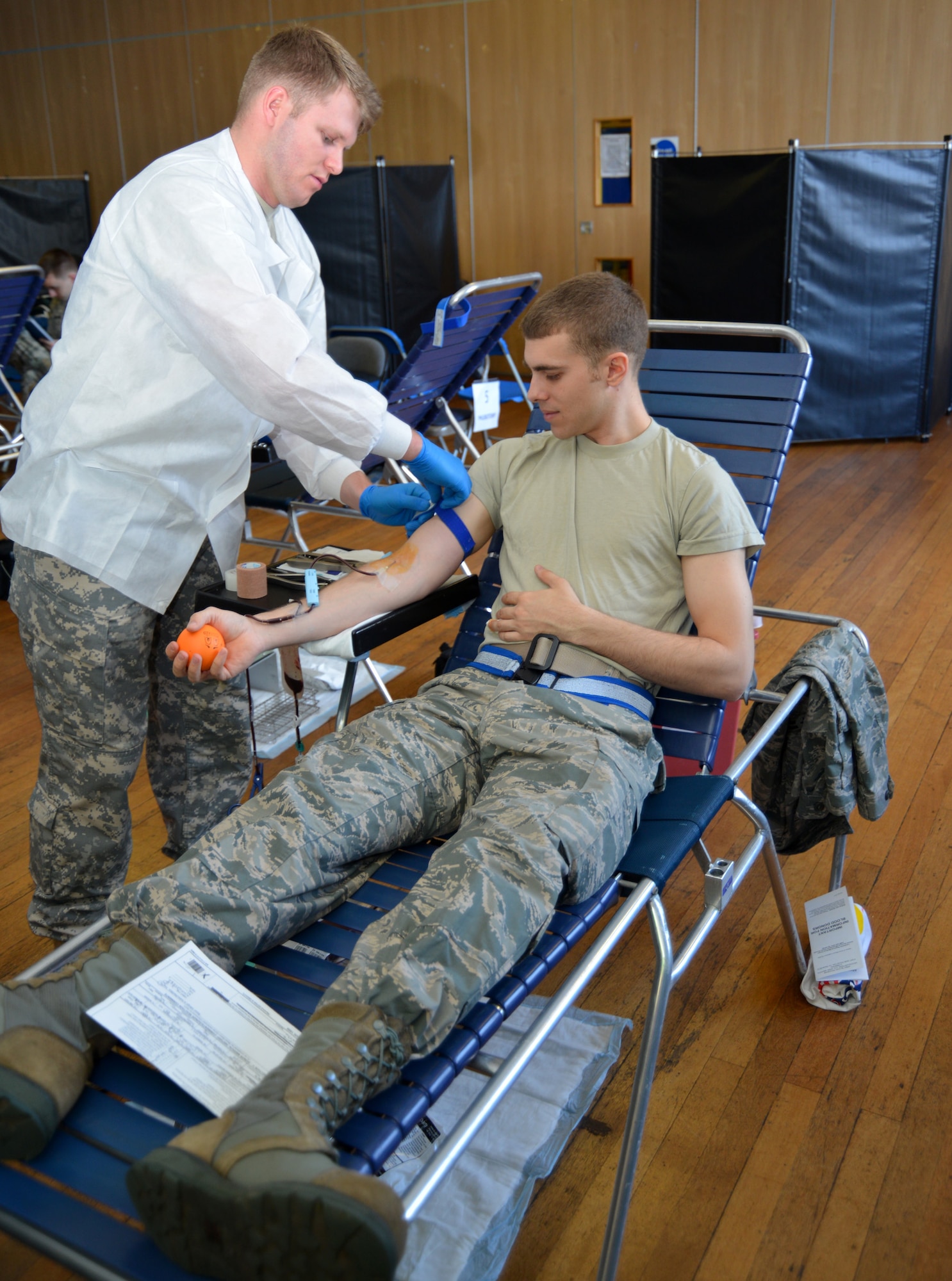 U.S. Army Spc. Matthew Ennis, left, 5501st U.S. Army Hospital, Landstuhl Regional Medical Center, Germany, lab technician from San Antonio, adjusts a band on the arm of U.S. Airman 1st Class Edgar Martinez, 352nd Special Operations Maintenance Squadron aircraft electrician from Orlando, Fla., during a blood drive Feb. 25, 2015, on RAF Mildenhall, England. The blood collected is specifically given to other U.S. service members and veterans. (U.S. Air Force photo by Karen Abeyasekere/Released)