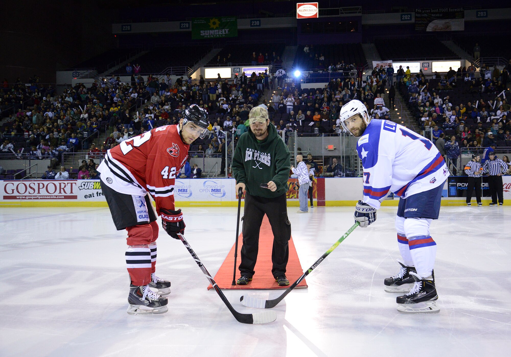Tech. Sgt. Kevin Parke (center), 96th Civil Engineer Squadron’s Explosive Ordnance Disposal flight, prepares to drop the puck during opening face-off between the Pensacola Ice Flyers and the Fayettville FireAntz hockey game, Feb. 21. The Ice Flyers were honoring America’s military with Military Appreciation Night at the Pensacola Civic Center.  Parke was injured by IED’s in two separate incidents, three months apart, in Afghanistan in 2010 and received two Purple Hearts. Parke was medically retired Feb. 24.  (Courtesy photo)
