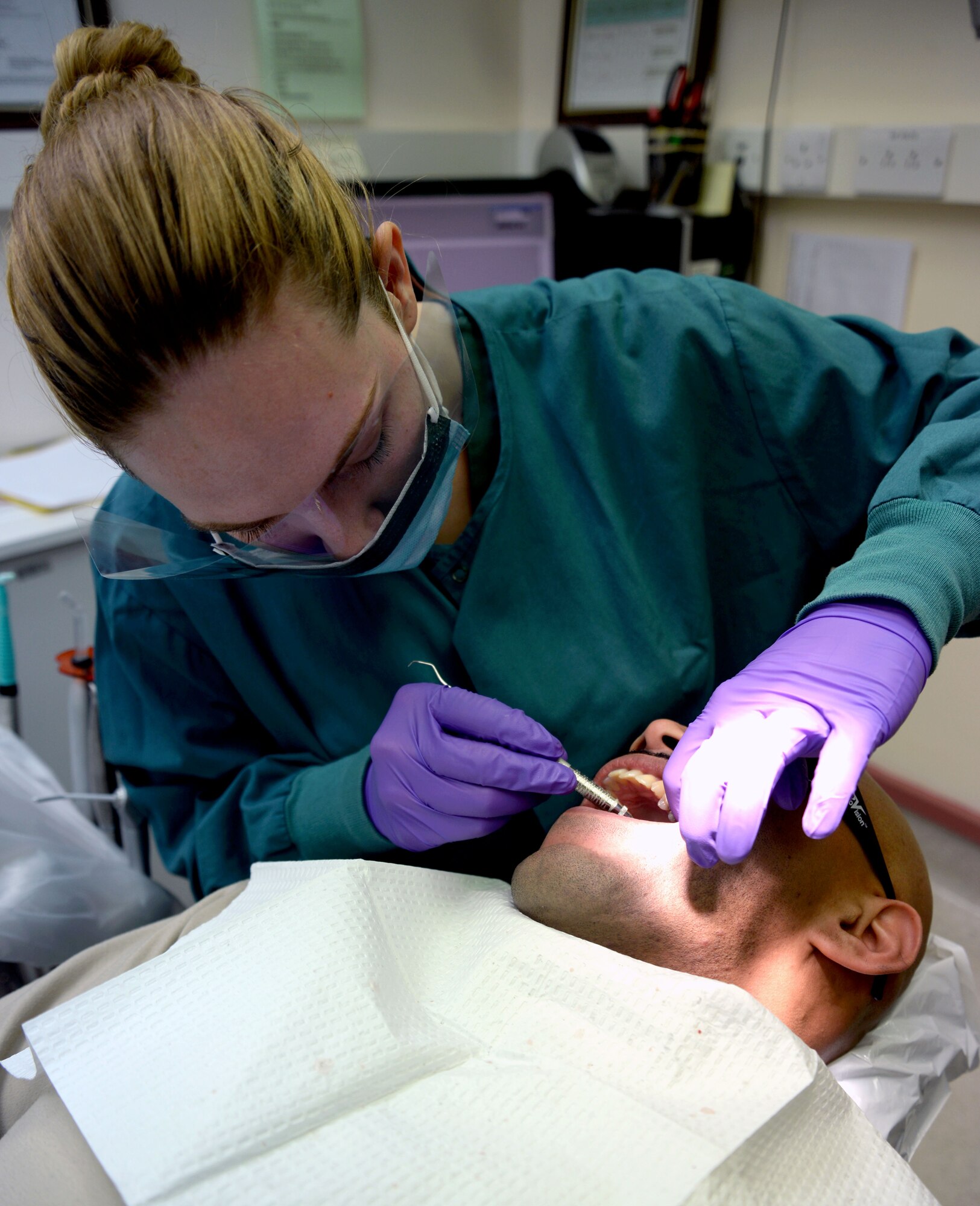 U.S. Air Force Airman 1st Class Charity Morejon, 48th Dental Squadron dental technician from Ocala, Fla., removes cement from around a temporary tooth Feb. 20, 2014 on RAF Mildenhall, England. Removing excess cement after installing a temporary tooth prevents irritation to the area. (U.S. Air Force photo by Senior Airman Christine Griffiths/Released)