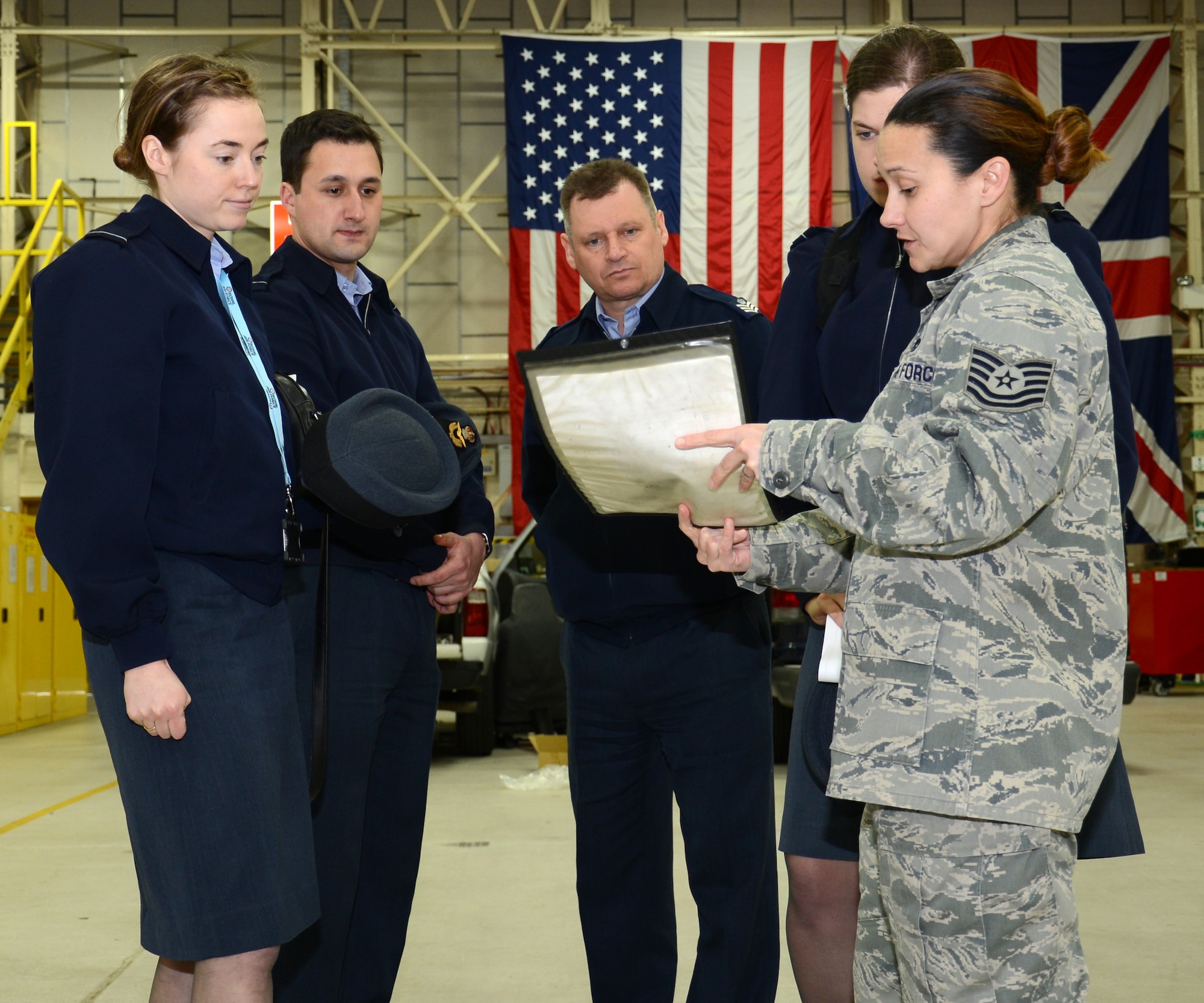 U.S. Air Force Tech. Sgt. Amy Chandler, right, 100th Logistics Readiness Squadron Vehicle Maintenance NCO in charge of general purpose vehicles from New Orleans, La., briefs Royal Air Force members on a vehicle and equipment work order, during a tour of the 100th LRS  Feb. 24, 2015, on RAF Mildenhall, England. RAF Logistics officers visited with members of the 100th LRS during a site tour to further improve relations between the two nations. (U.S. Air Force photo by Gina Randall/Released)