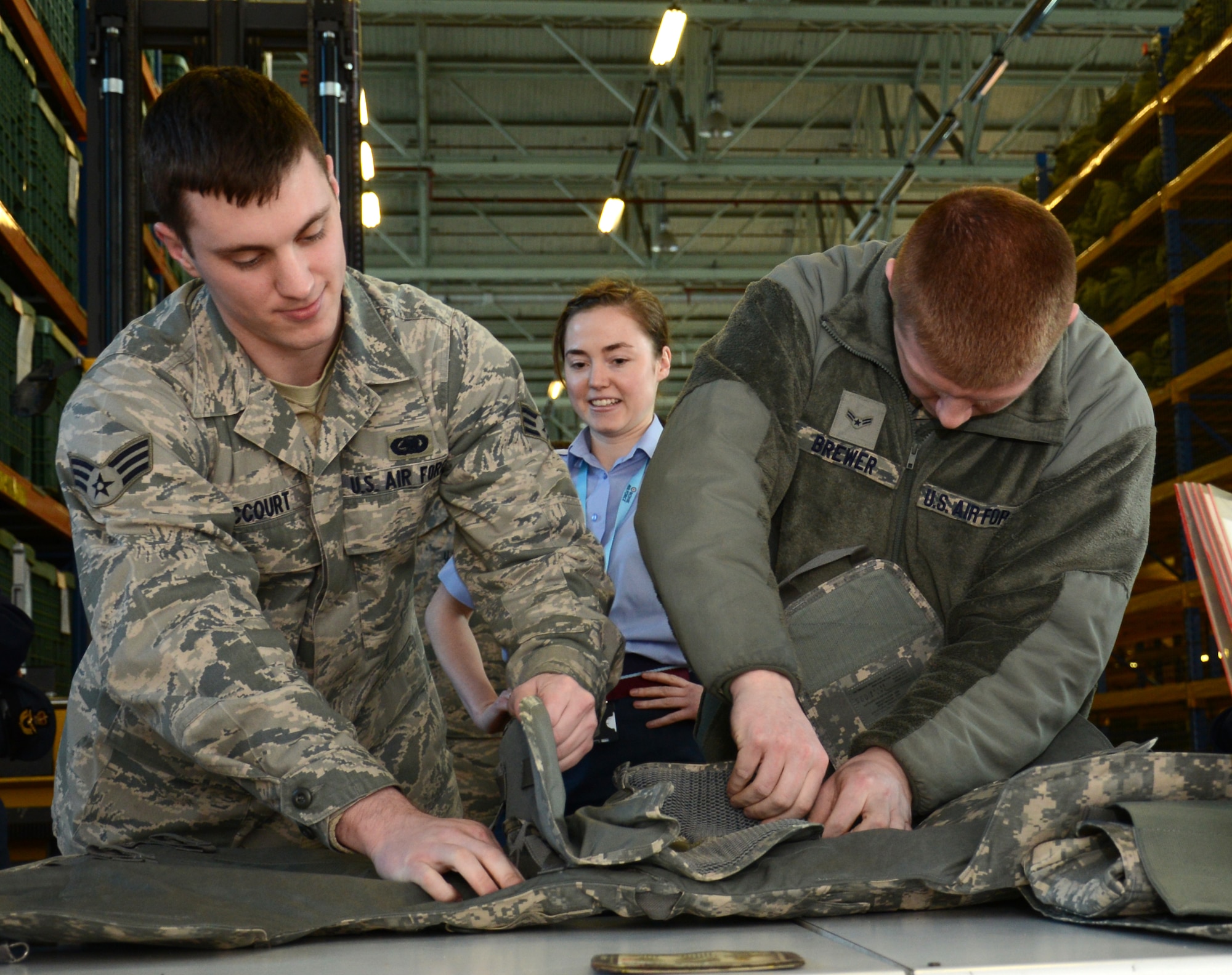 U.S. Air Force Senior Airman Landon McCourt, left, 100th Logistics Readiness Squadron Individual Protective Equipment journeyman from Temecula, Calif., and U.S. Air Force Airman 1st Class James Brewer, right, 100th LRS IPE mobility apprentice from Shawnee, Okla., prepare an improved outer tactical vest before Flying Officer Miranda Cope, center, tries it on Feb. 24, 2015, on RAF Mildenhall, England. Royal Air Force Logistics officers visited with members of the 100th LRS during a site tour to further improve relations between the two nations. (U.S. Air Force photo by Gina Randall/Released)