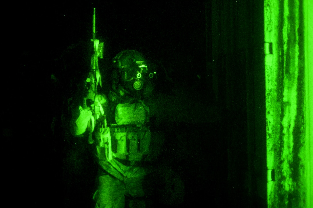 As seen through a night-vision device, an Army Green Beret soldier observes activities at a night assault on a mock outpost compound during a training mission held on Eglin Air Force Base in Northwest Florida, Feb. 20, 2015. The green berets are assigned to the 7th Special Forces Group, Airborne. The mission required a team of special forces soldiers to assault a mock drug-cartel outpost and document sensitive materials found inside.