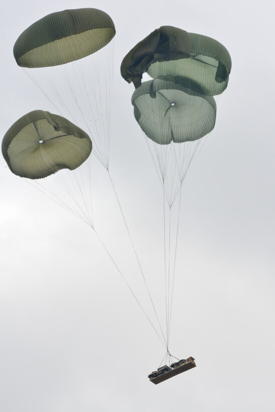 An M119 howitzer and a multipurpose vehicle hurtle down after being dropped by a U.S. Air Force C-130 Hercules on the 7th Army Joint Multinational Training Command's Grafenwoehr Training Area in Germany, Feb. 25, 2015. 