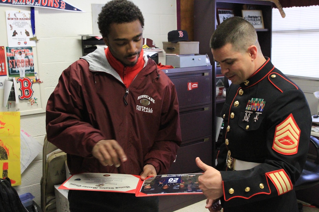 Gunnery Sgt. Manuel Beltran, a Marine Recruiter with Marine Recruiting Station Springfield, Mass., presents Taj-Amir Torres with a letter of appreciation for his participation in the Semper Fidelis All-American Bowl at Amherst High School on Feb 26. The Semper Fidelis All-American Bowl featured approximately 100 student athletes selected from across the country based on their athletic prowess, academic success and embodiment of the Marine Corps values of honor, courage and commitment. The game was played on Jan 4, at The StubHub Center in Carson, Calif. (Official Marine Corps photo by Staff Sgt. Richard Blumenstein). 