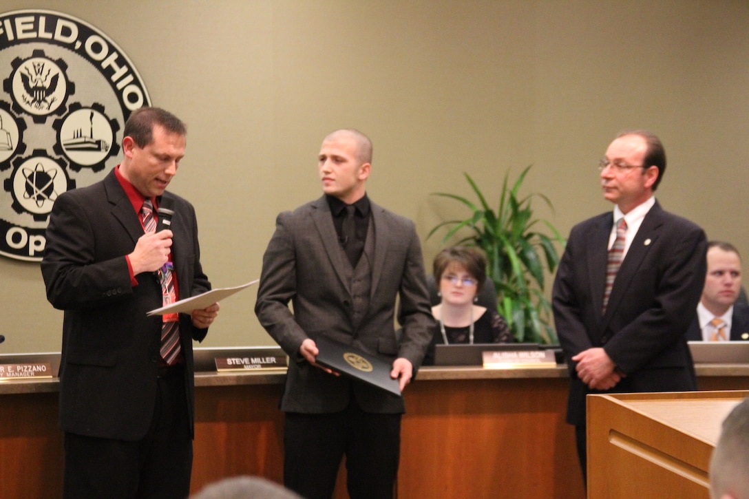Billy Smith (left), Principal of Fairfield High School, speaks to Fairfield city council during a city council meeting, Jan 9, about the courageous acts John Jones (center), an 18-year-old Fairfield High School senior, performed when a substitute teacher collapsed in class. Fairfield Mayor Steve Miller (right) proclaimed January 9, 2015 “John Jones Day.” After the proclamation, Jones participated in a ceremonial oath of enlistment to join the United States Marine Corps. (Marine Corps photo by Sgt. Jennifer Pirante/Released)