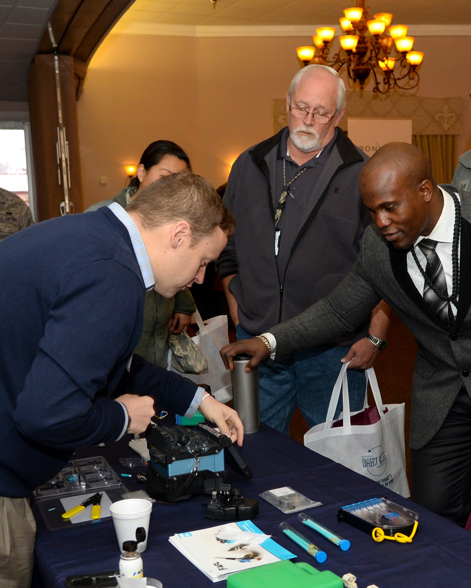 Visitors watch a vendor fuse together fiber optic cable during the 2015 Technology Expo on Barksdale Air Force Base, La., Feb. 26, 2015. The vendor used a fusion splicer kit to demonstrate the versatility of the kit to military members and government buyers. (U.S. Air Force photo/Senior Airman Benjamin Raughton)