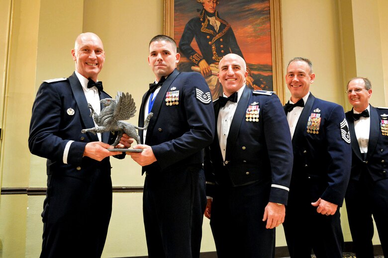 Maj. Gen. Timothy Zadalis, 618th Air Operations Center commander, presents the 43rd Airlift Group’s 2014 Noncommissioned Officer of the Year Gryphon trophy to Tech Sgt. Brian Fisher, 3rd Aerial Port Squadron, with Col. Kenneth Moss, 43rd Airlift Group commander and Chief Master Sgt. James Cope, 43rd Airlift Group superintendent, during the 440th Airlift Wing and 43rd Airlift Group 2014 Annual Awards Banquet held at the Fort Bragg Club, Feb. 21, Fort Bragg, N.C. while Brig. Gen. James Scanlan, 440th Airlift Wing commander looks on. (U.S. Air Force photo/Marvin Krause)