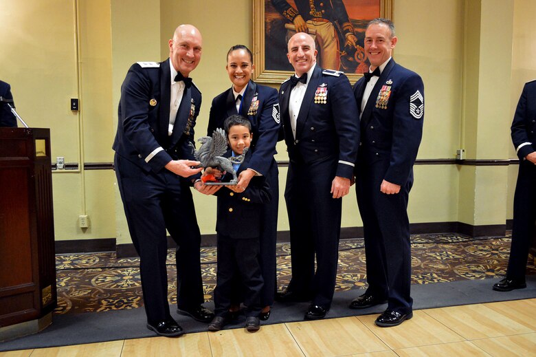 Maj. Gen. Timothy Zadalis, 618th Air Operations Center commander, presents the 43rd Airlift Group’s 2014 Senior Noncommissioned Officer of the Year Gryphon trophy to Master Sgt. Claudia Alvarez, 43rd Force Support Squadron, with her son, Alejandro, 7, with Col. Kenneth Moss, 43rd Airlift Group commander and Chief Master Sgt. James Cope, 43rd Airlift Group superintendent, during the 440th Airlift Wing and 43rd Airlift Group 2014 Annual Awards Banquet held at the Fort Bragg Club, Feb. 21, Fort Bragg, N.C. (U.S. Air Force photo/Marvin Krause)