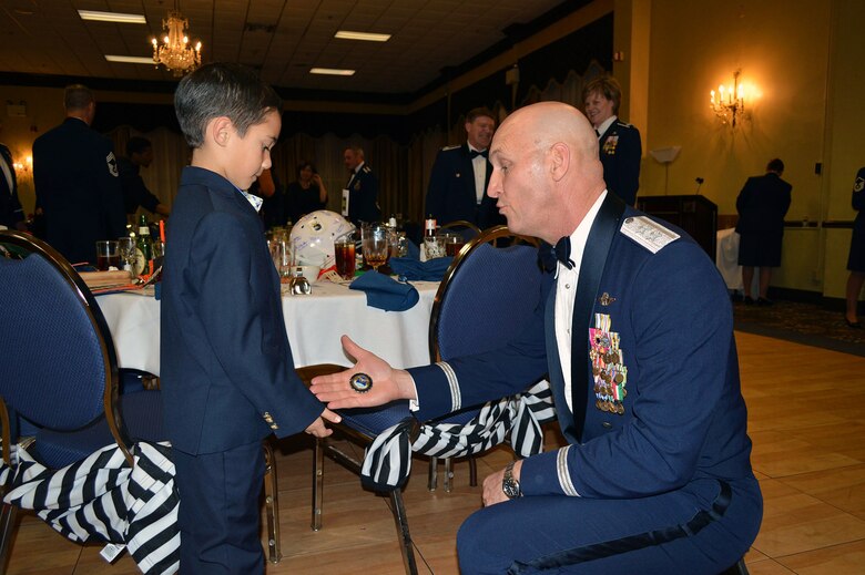 Maj. Gen. Timothy Zadalis, 618th Air Operations Center commander, Scott Air Force Base, lll., gives his commander’s coin to Master Sgt. Claudia Alvarez’s son, Alejandro, 7, after the 440th Airlift Wing and 43rd Airlift Group 2014 Annual Awards Banquet held at the Fort Bragg Club, Feb. 21, Fort Bragg, N.C. (U.S. Air Force photo/Marvin Krause)