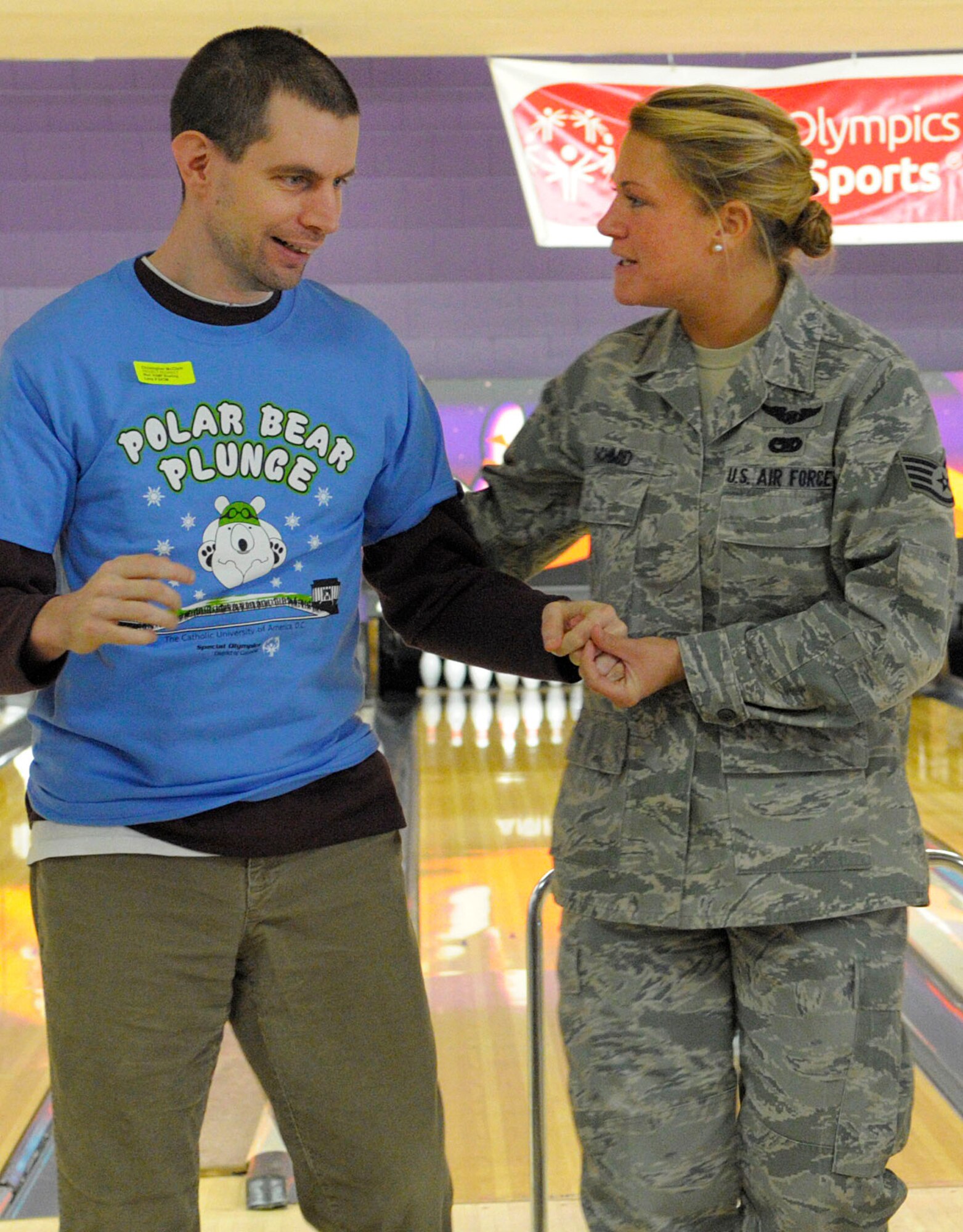 Staff Sgt. Brianna Schmid, 89th Airlift Wing flight attendant, walks with athlete Christopher McClain back to his seat during the annual D.C. Special Olympics Bowling Championship Feb. 25, 2015, in Hyattsville, Md. Airmen from the National Capital Region hosted the day’s competition cheering on athletes and providing assistance. (U.S. Air Force photo/Michael Martin)