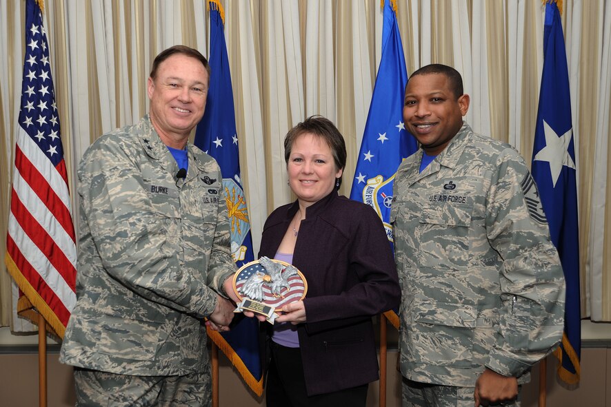 Air Force District of Washington Commander Maj. Gen. Darryl Burke and Command Chief Master Sgt. Farrell Thomas present Annette Bonaro with the Headquarters AFDW Annual Award Civilian Volunteer of the Year trophy at Joint Base Andrews, Md. Bonaro is the AFDW unit deployment manager. During 2014 Bonaro managed Care Package Central and was active participant with Wreaths Across America, Christmas in April, and National Rebuilding Day. (U.S. Air Force photo/James E. Lotz) 