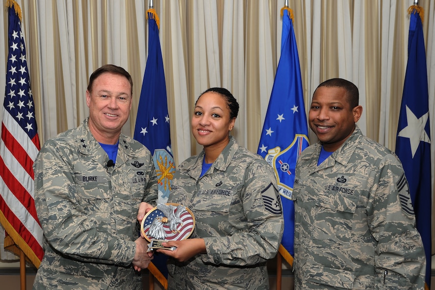 Air Force District of Washington Commander Maj. Gen. Darryl Burke and Command Chief Master Sgt. Farrell Thomas present Senior Master Sgt. Dawn Woodard with the Headquarters AFDW Annual Award SNCO of the Year trophy at Joint Base Andrews, Md. Woodard is assigned to the AFDW Manpower, Personnel, and Services directorate. During 2014 Woodard led the Joint Warfare Analysis Center Civilian Training Program and trained 22 additional duty training managers.  (U.S. Air Force photo/James E. Lotz) 