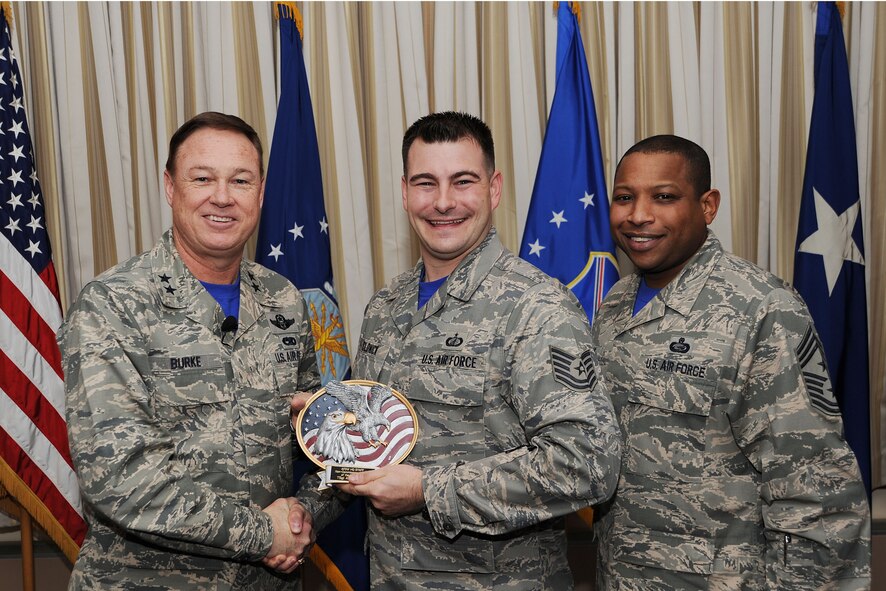 Air Force District of Washington Commander Maj. Gen. Darryl Burke and Command Chief Master Sgt. Farrell Thomas present Tech. Sgt. Adam Klonick with the Headquarters AFDW Annual Award NCO of the Year trophy at Joint Base Andrews, Md. Klonick is assigned to the AFDW Contracting directorate. During 2014 Klonick managed the $12 million AFDW government purchase card level three portfolio and increased productivity by 25 percent.  (U.S. Air Force photo/James E. Lotz) 