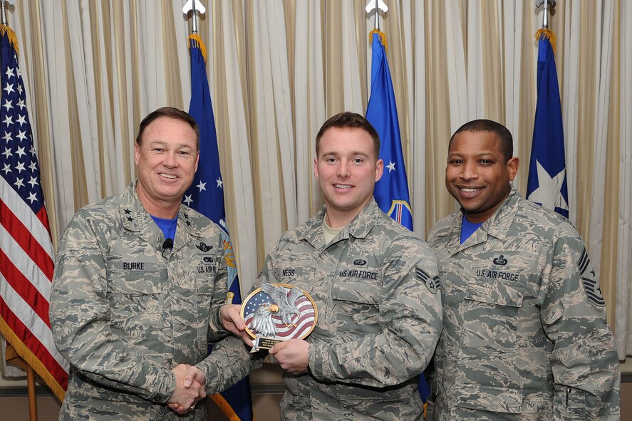 Air Force District of Washington Commander Maj. Gen. Darryl Burke and Command Chief Master Sgt. Farrell Thomas present Senior Airman Andrew Ness with the Headquarters AFDW Annual Award Airman of the Year trophy at Joint Base Andrews, Md. Ness is assigned to the AFDW Contracting directorate. During 2014 Ness managed 72 contract actions valued at $239 million and led his division in contracting action execution. (U.S. Air Force photo/James E. Lotz) 