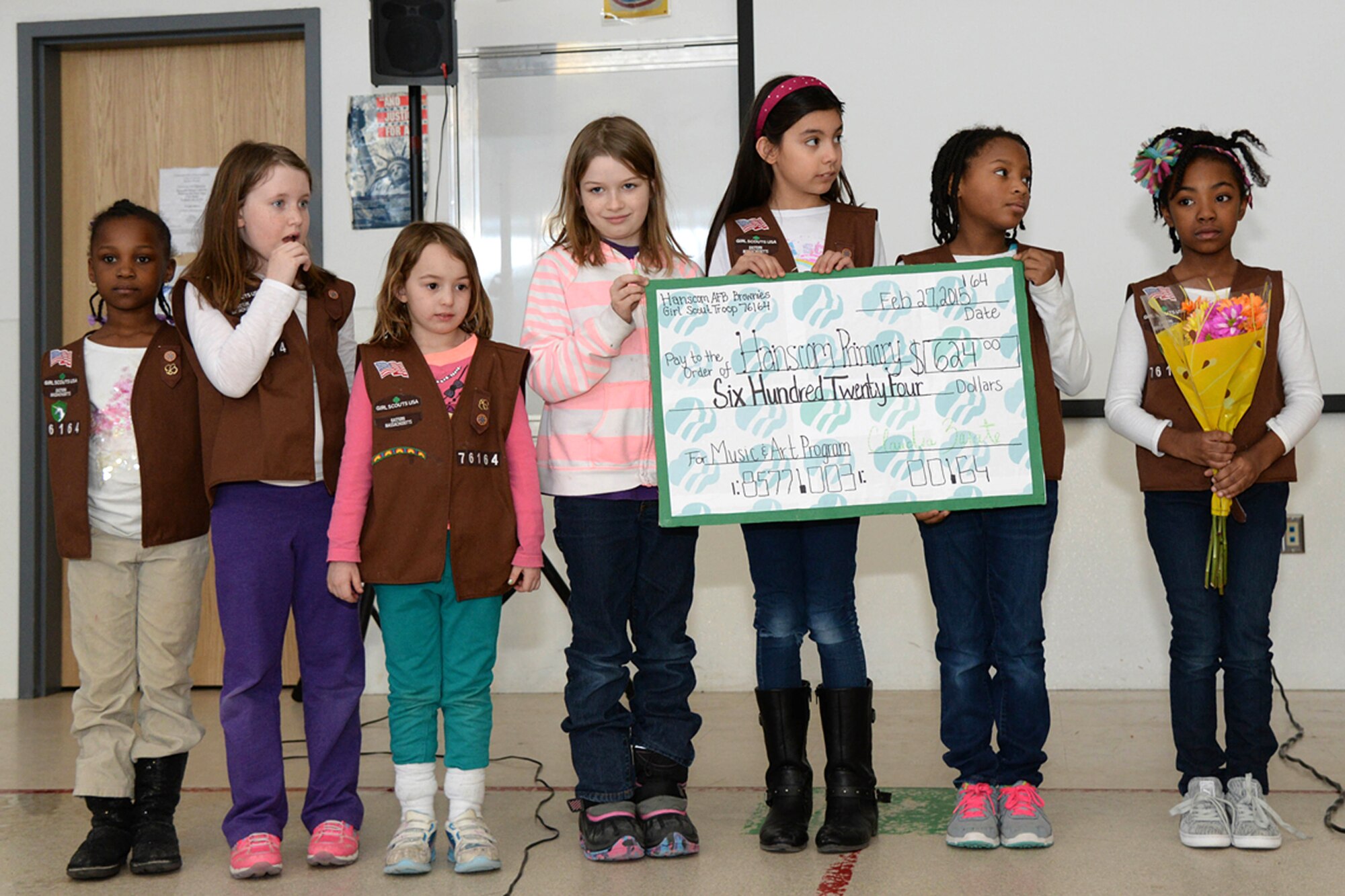 Members of the Hanscom Air Force Base Girls Scout Troop 76164 present the Hanscom Primary School Music and Art Program with a check for $624 at the school during an assembly Feb. 27. The brownies raised the money as part of a Take Action Project. Members identified a need in their community, developed a plan to address the need, organized and completed an activity to make an improvement by learning goal setting, advertising, product pricing and product production by having a bake sale at the base commissary. (U.S. Air Force photo by Linda LaBonte Britt)
