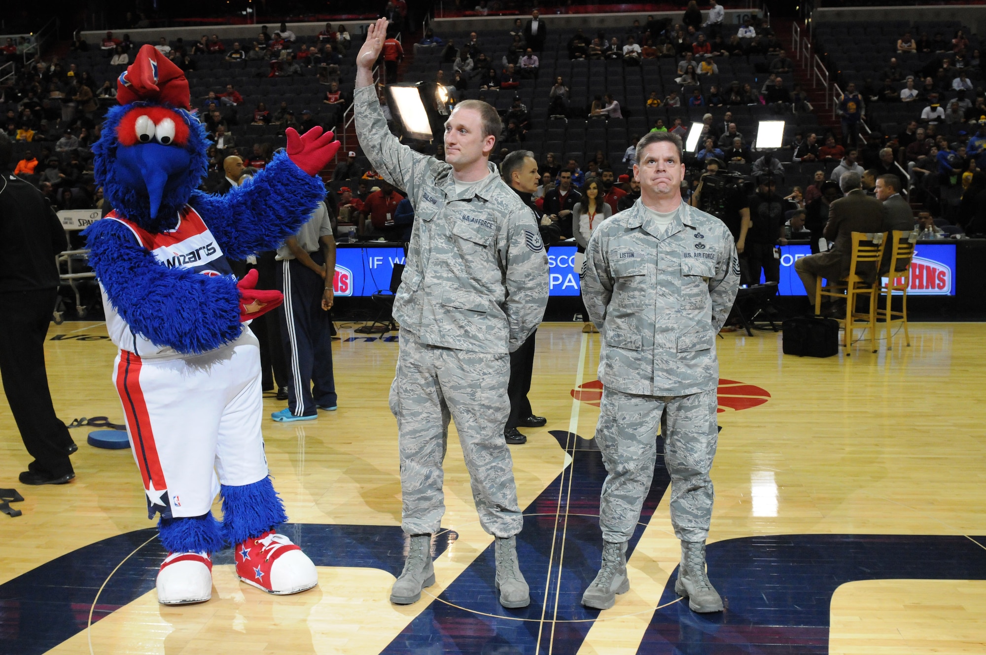 Tech. Sgt. Justin Foulsham waves to the crowd as he and fellow D.C. Air National Guard member Senior Master Sgt. William Liston are honored for their service prior to the Washington Wizards home game against the Golden State Warriors, Feb. 24. Both Foulsham and Liston are 2014 DCANG annual award winners.  (Air National Guard photo by Master Sgt. Craig Clapper)