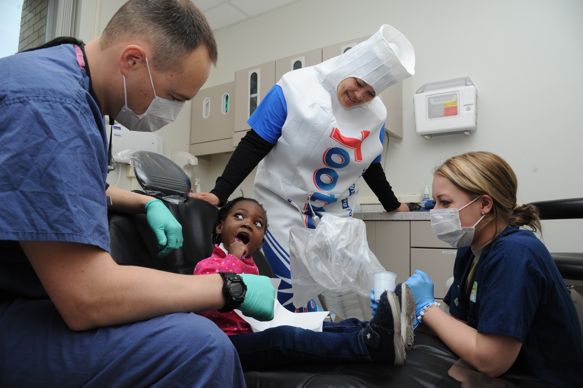Gabriella Cox brushes her teeth as Capt. (Dr.) Rob Wake, 81st Dental Squadron advanced education in general dentistry resident, Felicia Haper, 81st DS dental assistant, and Airman 1st Class Jessica Jarosz, 81st DS dental assistant, watch during the 5th annual Give Kids a Smile Day Feb. 25, 2015, at the dental clinic, Keesler Air Force Base, Miss.  The clinic provided approximately $14,000 in care at the free screening. The event included dental exams and cleanings for children two and older. Gabriella is the daughter of Airman 1st Class Darryl Cox, 334th Training Squadron student.  (U.S. Air Force photo by Kemberly Groue)