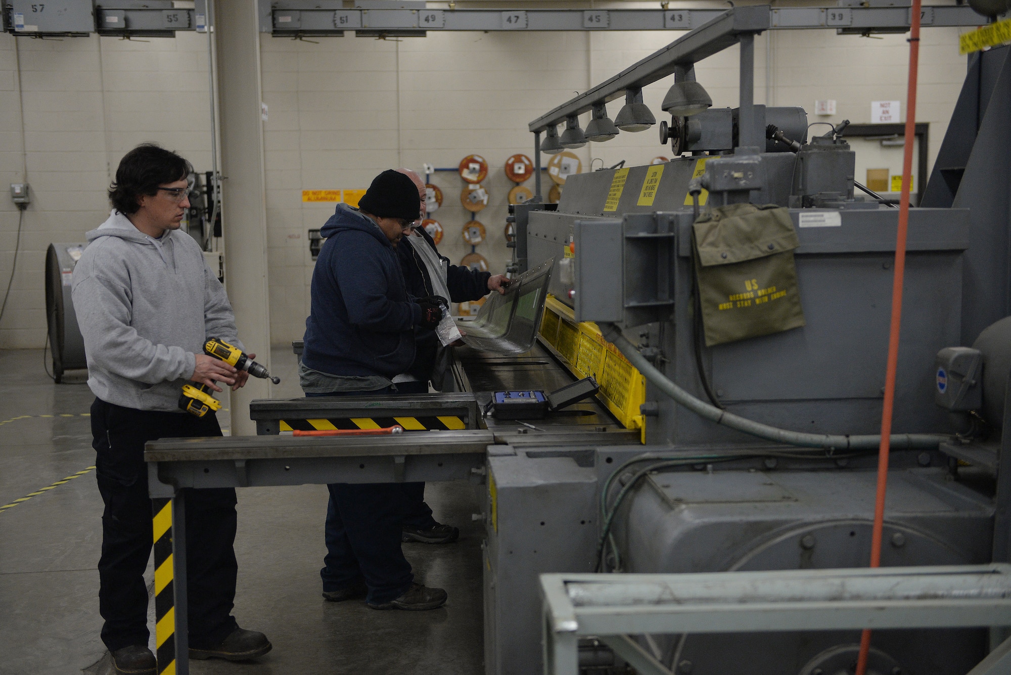 ALTUS AIR FORCE BASE, Okla. – Gary Farmer, Joe Balderas and Greg Crosswhite, 97th Maintenance Directorate A-Team sheet metal mechanics, install fastener retainers on a newly trimmed U.S. Air Force C-17 Globemaster III cargo aircraft pylon engine fairing, at Hangar 517, Feb. 23, 2015. Fabrication is in charge of maintaining and repairing the C-17, as well as, the U.S. Air Force KC-135 Stratotanker refueling aircraft, and it is responsible for welding, machining, sheet metal, composite structures, metal tubing, flight control cales and corrosion control. (U.S. Air Force photo by Airman 1st Class Megan E. Acs/Released)
