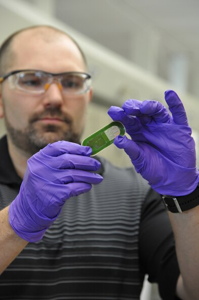Air Force Research Laboratory researcher, Dr. Joshua Hagen, holds up a sweat sensor prototype.  AFRL’s 711th Human Performance Wing and the University of Cincinnati conducted the first successful human trials of the usable sweat sensor at Wright-Patterson Air Force Base, Ohio, Feb. 11. The results of the trial are promising, not only for future 711th research efforts, but for the Air Force and its sister services. The team is already working on future sensor generations, which could conceivably measure more biomarkers like true physical exhaustion, stress or fatigue.  (U.S. Air Force photo by Michele Eaton/88 
ABW Public Affairs/Released)