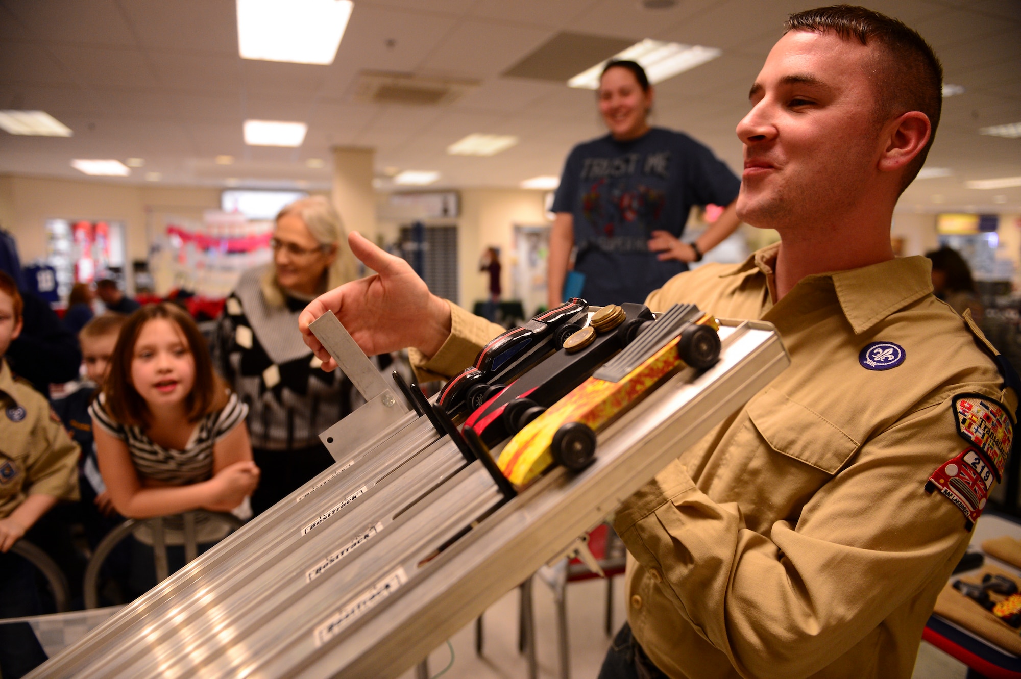 Tech. Sgt. Scott Okelberry, 352nd Special Operations Group facility manager, operates the boxcar racetrack lever during the annual Cub Scout Pack 219 Pinewood Derby at the Exchange on Royal Air Force Lakenheath, England, Feb. 24, 2015. The track is specially designed to release all entries equally and record precise finish times. (U.S. Air Force photo by Senior Airman Nigel Sandridge/Released) 