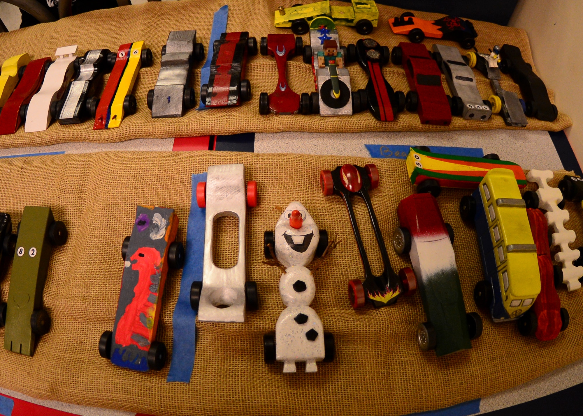 Handmade cars sit on display for the Cub Scout Pack 219 Pinewood Derby at the Exchange on Royal Air Force Lakenheath, England, Feb. 24, 2015. The Pinewood Derby is a yearly event in which members of the scouts race handcrafted cars carved from wood. (U.S. Air Force photo by Senior Airman Nigel Sandridge/Released)