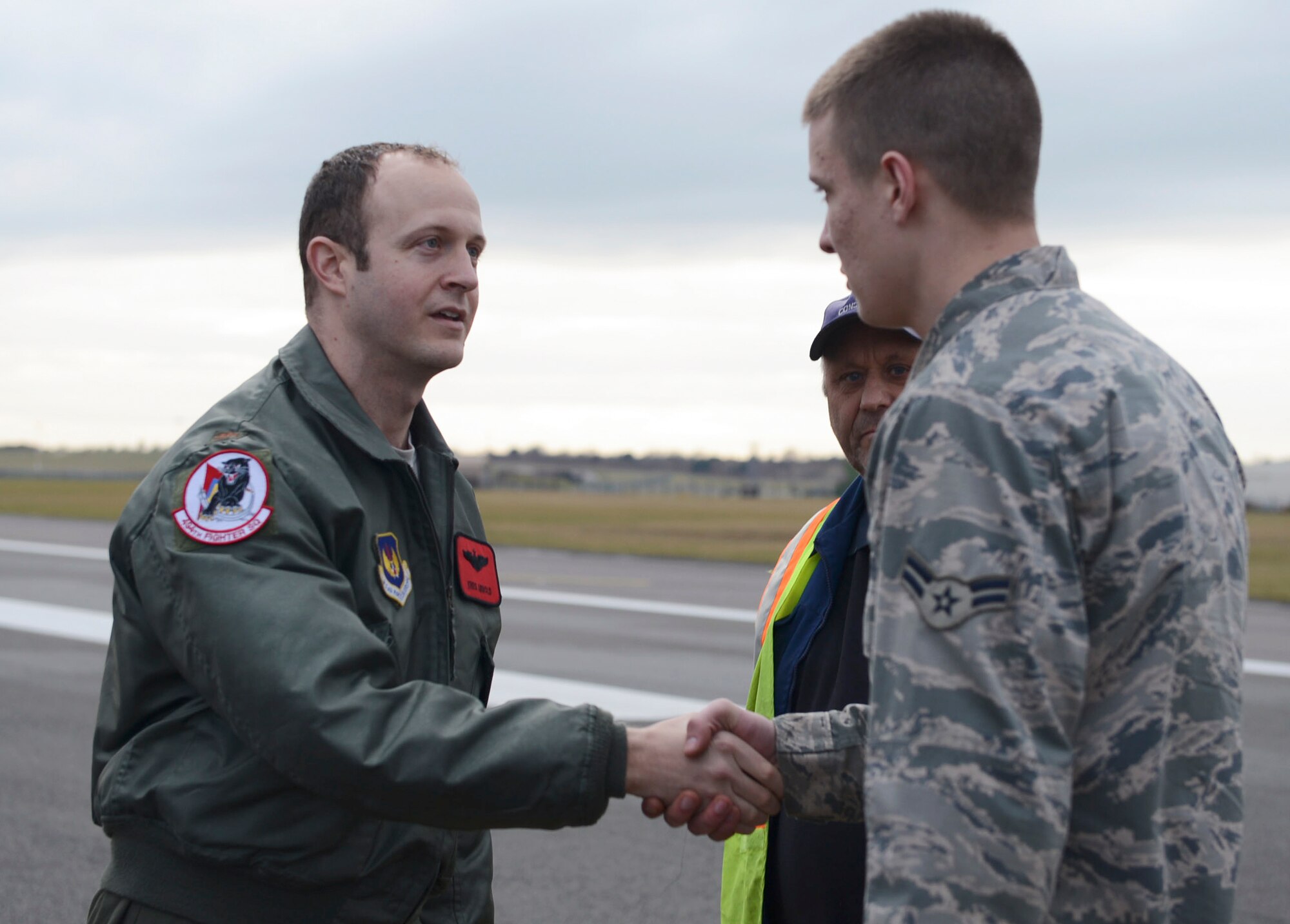 Maj. Kreg Arnold, 494th Fighter Squadron assistant director of operations, presents a coin to Airman 1st Class Jake Puzzuto, 48th Civil Engineer Squadron heavy equipment operator, Feb. 25, 2015, at Royal Air Force Lakenheath, England. The achievement coin is given as a reward for outstanding service or performance of duty. Puzzuoto along with other crew members made an emergency repair to the RAF Lakenheath runway so pilots could land safely. (U.S. Air Force photo by Airman 1st Class Dawn M. Weber/Released)