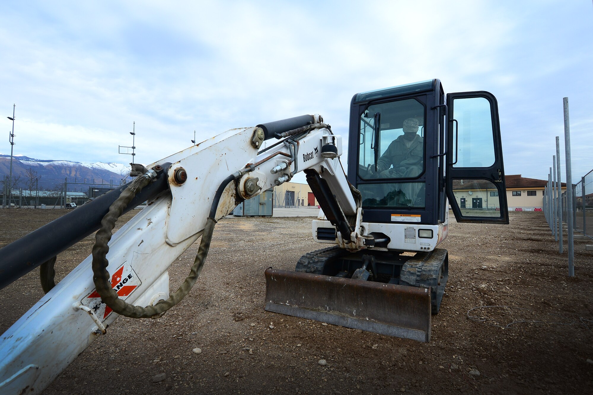 U.S. Air Force Staff Sgt. Michael Gilmore, 31st Civil Engineer Squadron pavements and construction supervisor, moves an arm on a bobcat excavator, Feb. 23, 2015, at Aviano Air Base, Italy. The unit has 13 Airmen responsible for several construction operations around base to include airfield sweeping, crane operations and snow removal. (U.S. Air Force photo by Senior Airman Matthew Lotz/Released)