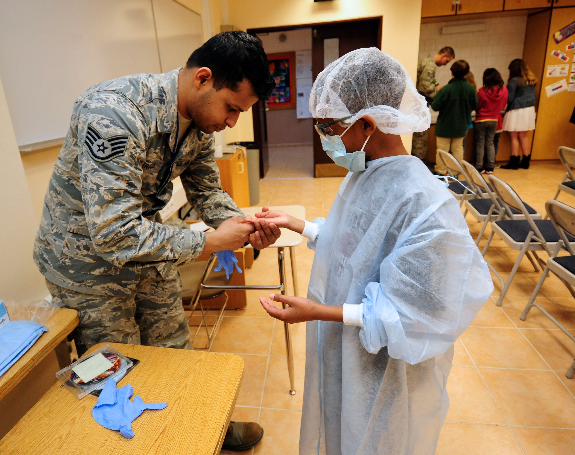 Staff Sgt. Mohammad Farooq, 39th Medical Operations Squadron dental assistant, helps Tyree Lindsey, third-grade student, dress up as a dentist Feb. 24, 2015, at Incirlik Air Base, Turkey. Incirlik Unit School students attended a lesson on dental health as part of National Children’s Dental Health Month. (U.S. Air Force photo by Senior Airman Krystal Ardrey/Released)