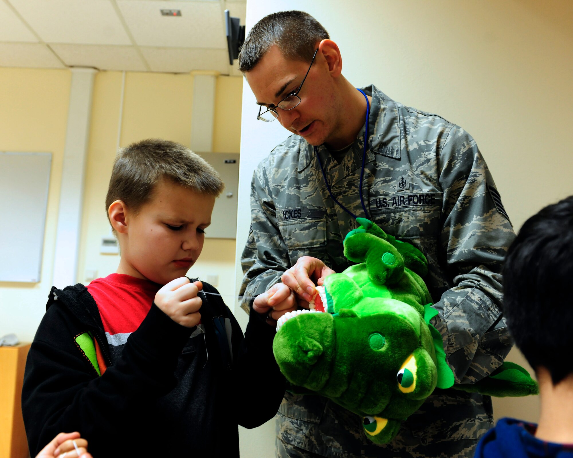 Tech. Sgt. Doug Ickes, 39th Medical Operations Squadron dental lab technician, shows Michael Leath, fourth-grade student, proper flossing techniques using a toy alligator Feb. 24, 2015, at Incirlik Air Base, Turkey. Ickes visited the school as part of National Children’s Dental Health Month to teach students about the importance of dental hygiene. (U.S. Air Force photo by Senior Airman Krystal Ardrey/Released)
