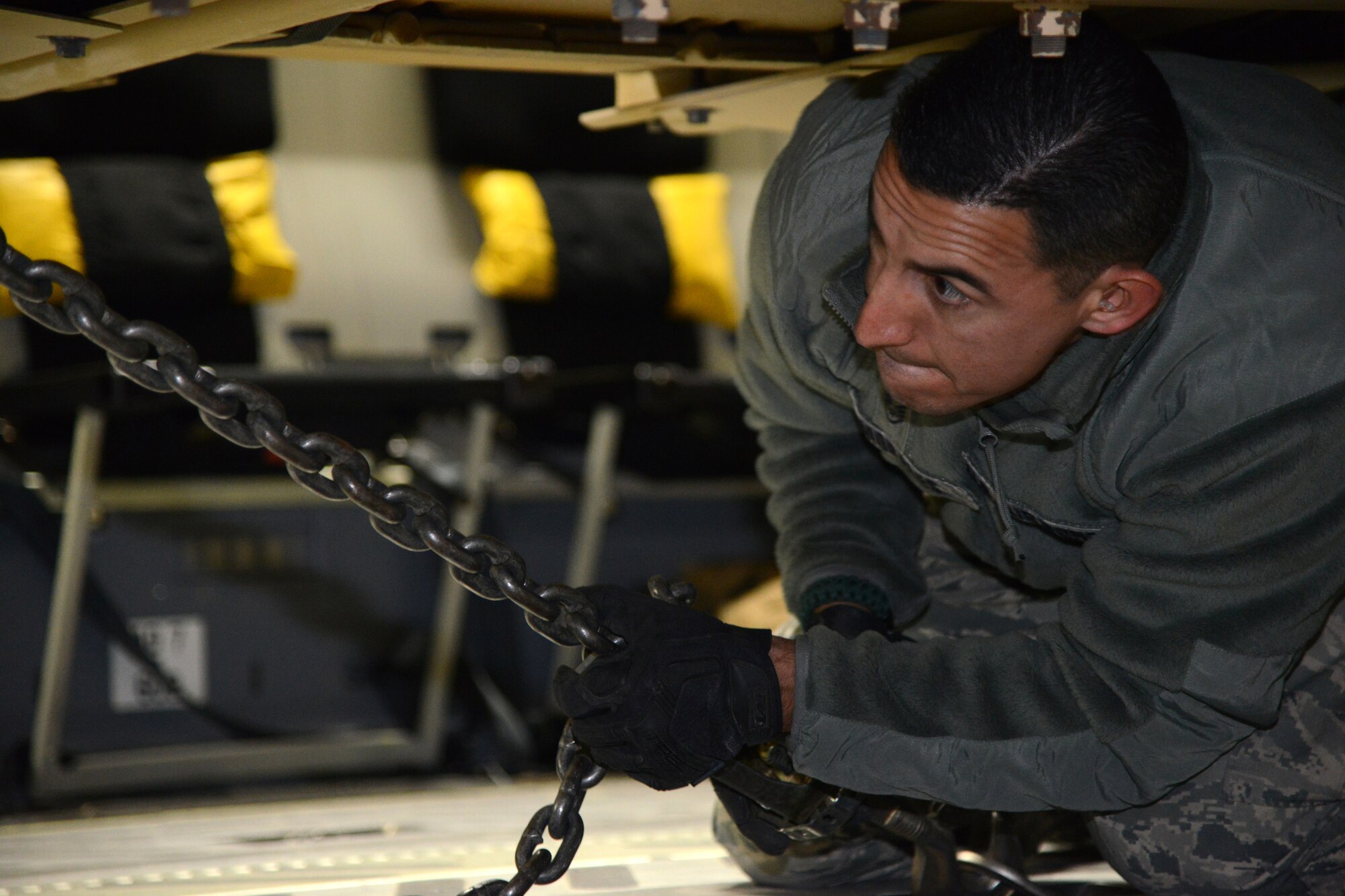 Staff Sgt. Omar Morales, 386th Expeditionary Logistics Readiness Squadron, secures the chains on one of two Mine Resistant Armored Personnel carriers on a C-17 Globemaster III bound for Erbil, Iraq, Dec. 30, 2014. The MRAPs are for the Iraqi Security Forces and Peshmerga to aid in the fight against Daish. (U.S. Air Force photo by Tech. Sgt. Jared Marquis/released)