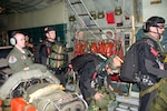 Pararescuemen from the 129th Rescue Wing of the California Air National Guard prepare to jump from the rear door of a Coast Guard C-130 Hercules airplane about 1,400 miles southwest of San Diego, Calif., April 1, 2010. The Coast Guard and Air National Guard worked together to respond to medevac an injured 57-year-old man by dropping four pararescuemen, an inflatable boat and other rescue and survival equipment.